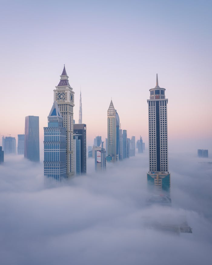 About A breathtaking aerial view of Dubai's iconic skyline emerging through the clouds at sunrise.